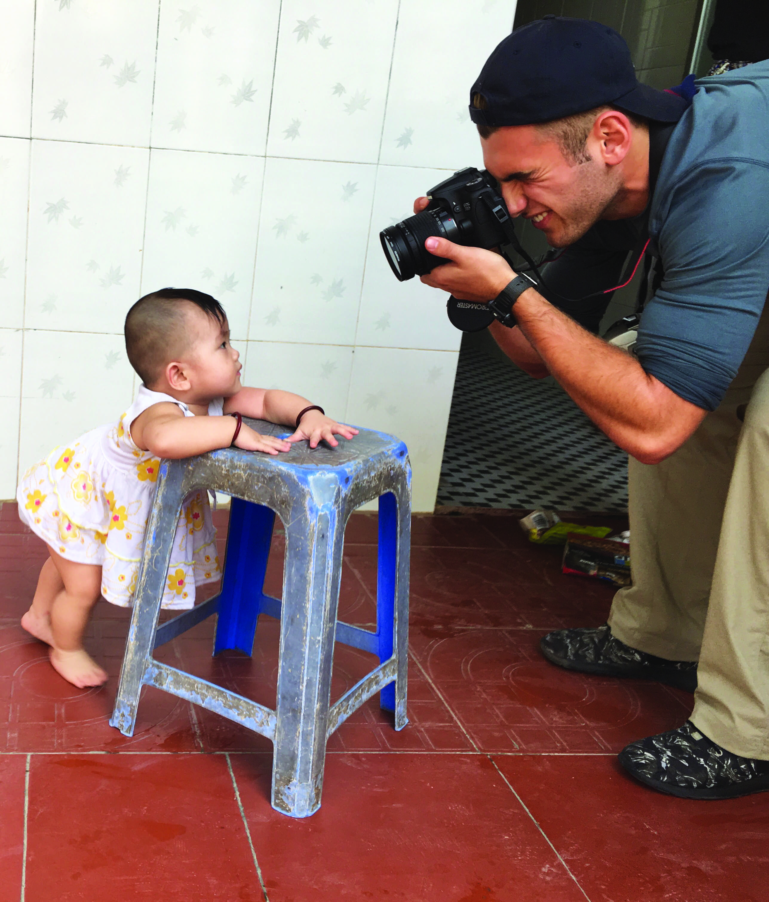 CAM AND HIS CAM: Cameron Welther ’17 photographs an infant at a Buddhist orphanage just outside of Saigon. Welther and 15 other students handed out toys and played with the children there. The orphanage was one of the many sites in Vietnam that the students who were on the Digital Storytelling Adventure trip visited. Credit: Lauren Kim/Chronicle