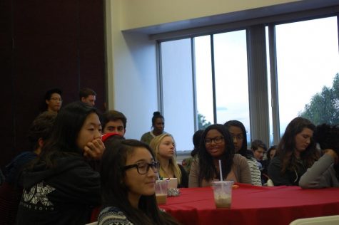 Students watching the performances sit at one of the several tables set up in the lounge for Coffee House. 