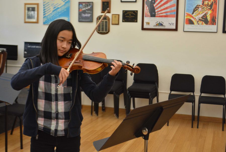 Anna Gong 18 practices a violin solo in the orchestra room. Credit: Claire Dennis/Chronicle