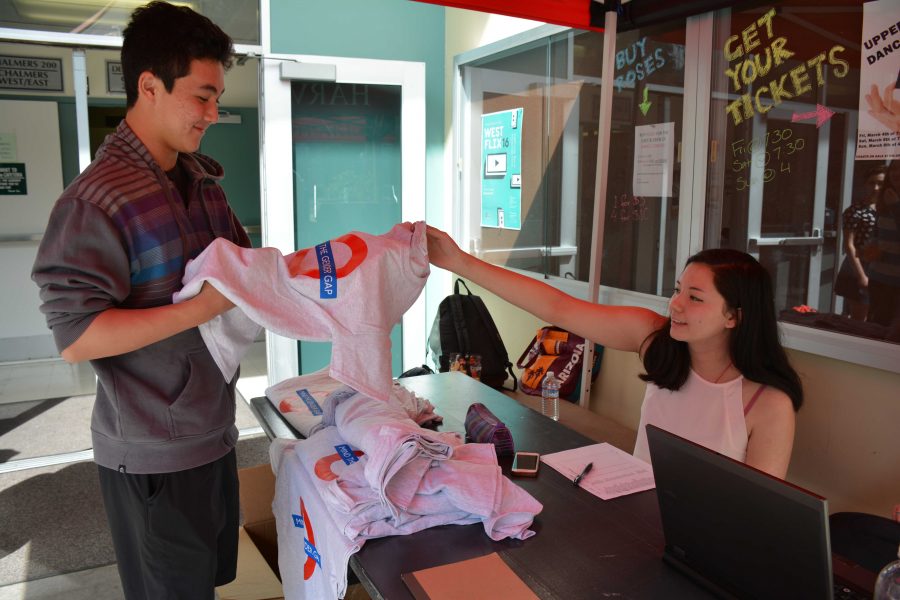 : La Femme club member Maggie McCarthy ’17 sells a “Mind the Gender Gap” T-shirt to Jacob Tucker ’17. The club tried to design a shirt that can be worn by both boys and girls to spread the message of gender equality to everyone on campus.  Credit: Teresa Suh
