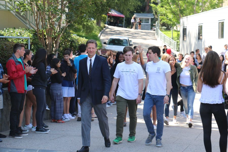 Head of Upper School Audrius Barzdukas, William Ruppenthal 16 and Jake Zimmerman 16 exit Taper Gym after their last First and Third Wednesday Assembly. The seniors and Barzdukas walk between sophomores and juniors for the end of the year senior walk. Credit: Pavan Tauh/Chronicle