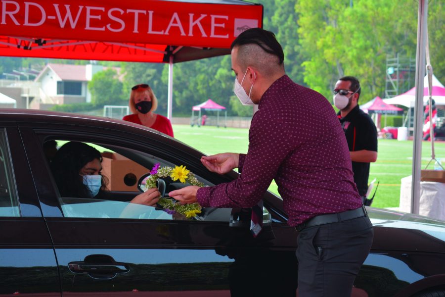 Mohona Ganguly ’21 receives a floral wreath from upper school dean Celso Cárdenas from inside her car. The celebration was held for seniors as a drive-thru due to the coronavirus Sept. 13.
Credit: Crystal Baik