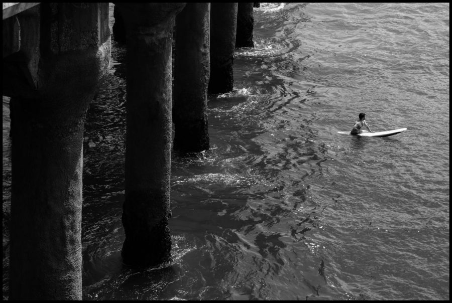 A+black-and-white+photograph+taken+by+Baxter+Chelsom+23+shows+a+surfer+paddling+out+on+his+board+in+an+attempt+to+catch+a+wave.