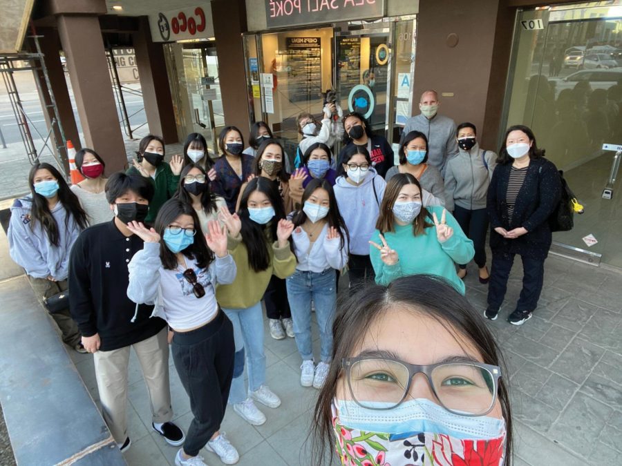 Students wearing masks meet in front of a Sawtelle Boulevard store-front during their event. 