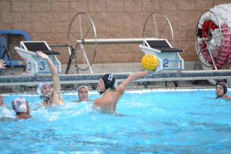 Boys water polo player Jaxson Tierney 23 sets up to shoot the ball in the face of numerous defenders.