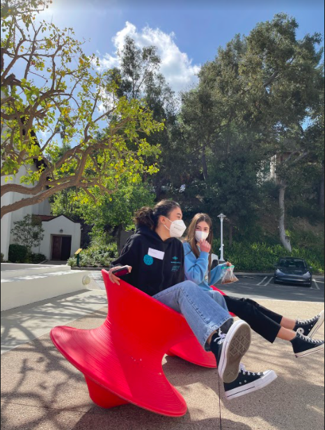 In between online classes on campus, Chloe Fribourg 23 and Lauren LaPorta 23 catch up as they spin together in the bright red chairs outside the visual arts department March 9. 