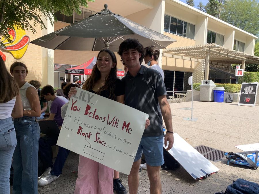 Following his homecoming ask, Avi Carson ’22 poses with Lily Saada ’22, who holds Carsons school-colored handmade poster, which is full of Taylor Swift inspired references and puns. 