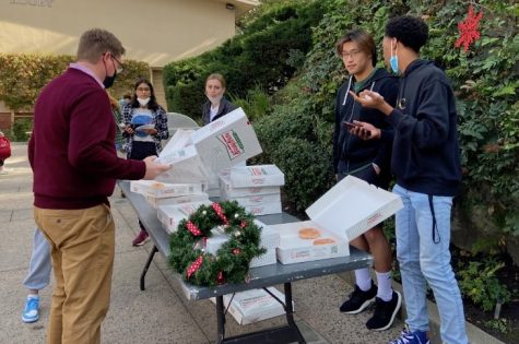 Dean of Students and ISIR Teacher Jordan Church converses with Matthew Messaye 22, before grabbing a Krispy Kreme donut from Community Council member Andrew Choe 22.