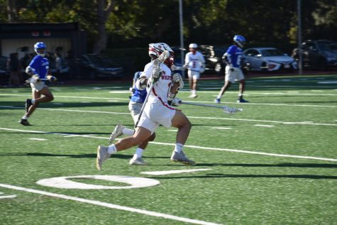 A varsity lacrosse player runs next to an opponent in the teams game against Culver City. 