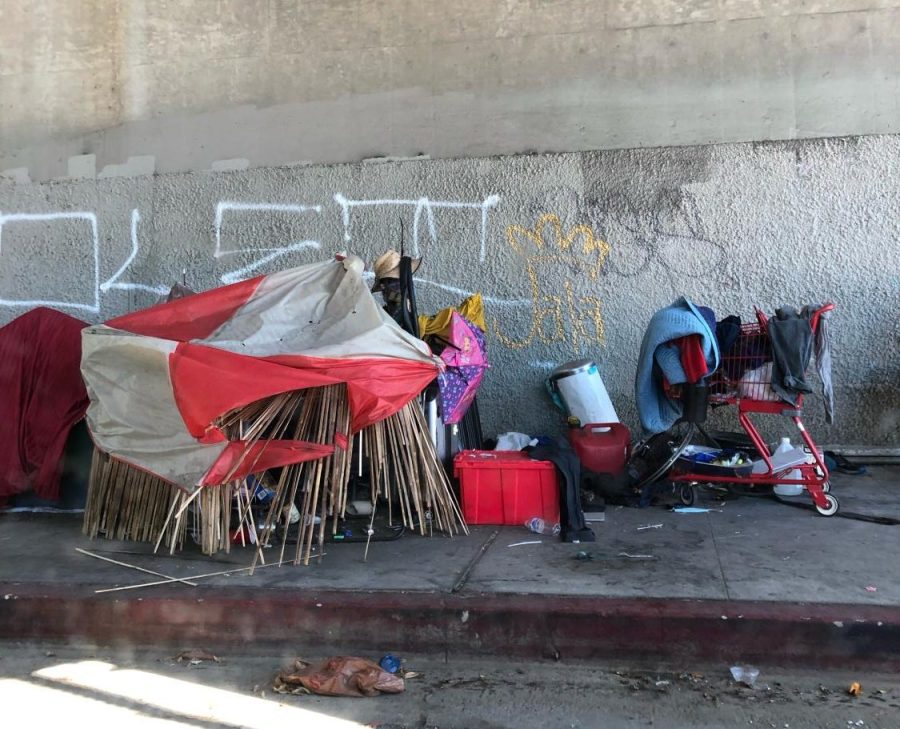 Underneath a freeway, people experiencing homelessness build shelters. 