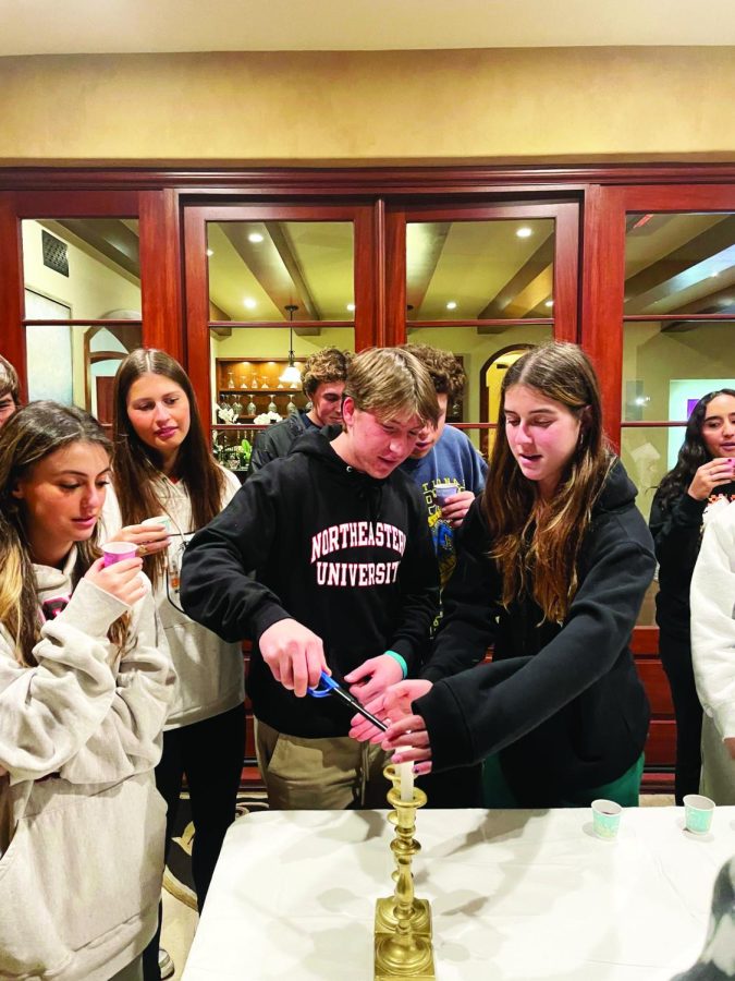 LIGHTING IT UP: Sammy Glassman ’24 and Danielle Leibzon ’24 light a candle with other members of JFA as a part of event celebrations.