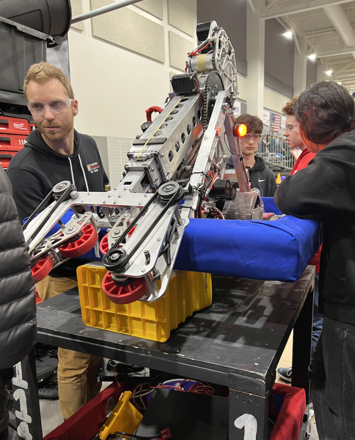 Members of the Upper School Robotics Team and Mathematics Teacher and Robotics Coach Andew Theiss gather around their robot before it competes at the Central Valley Regional Tournament. 