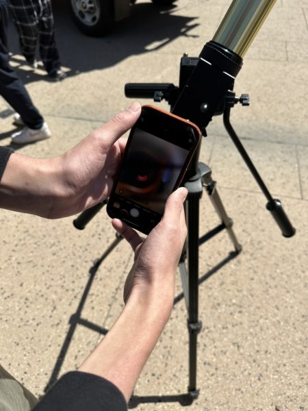 The school gathered along the Quad and viewed the solar eclipse through telescopes and solar eclipse glasses. Asher Meron 25 attempts to take a picture of the solar eclipse through a telescope.