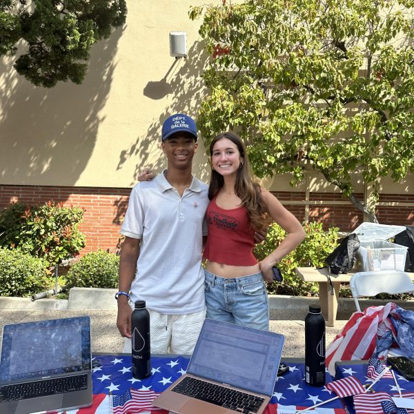 Alexander Hudlin '26 and Priscilla Johnson '26 stand together behind their voter registration booth. 