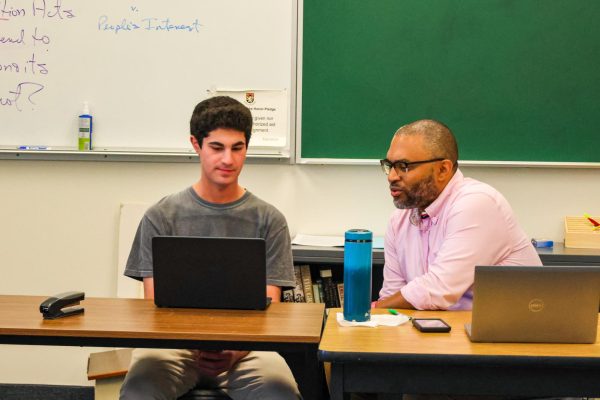 History Teacher Erik Wade works with a student during a meeting. The administration is discussing possible revisions to the school day to free up teacher schedules and plan more community-building events.