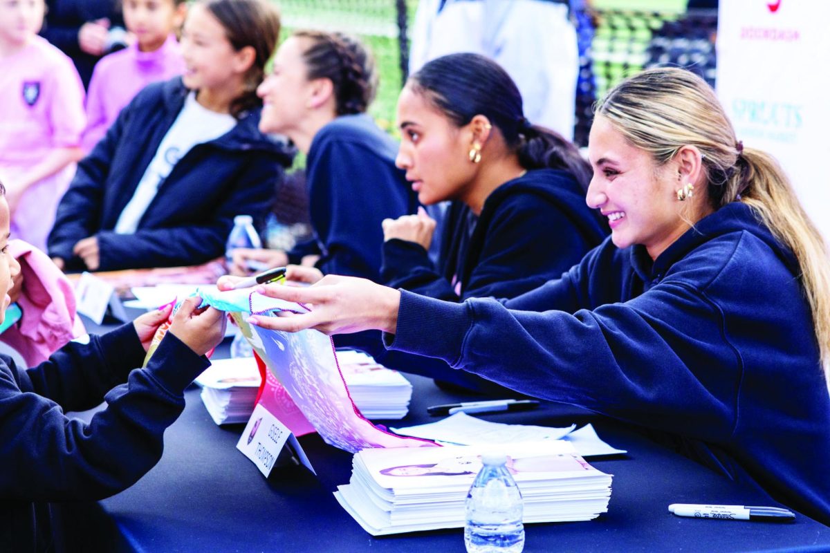 SIGNING SUPPORT: Gisele Thompson ’24 and Alyssa Thompson ’23
greet young fans and sign autographs during a community event Feb. 6.