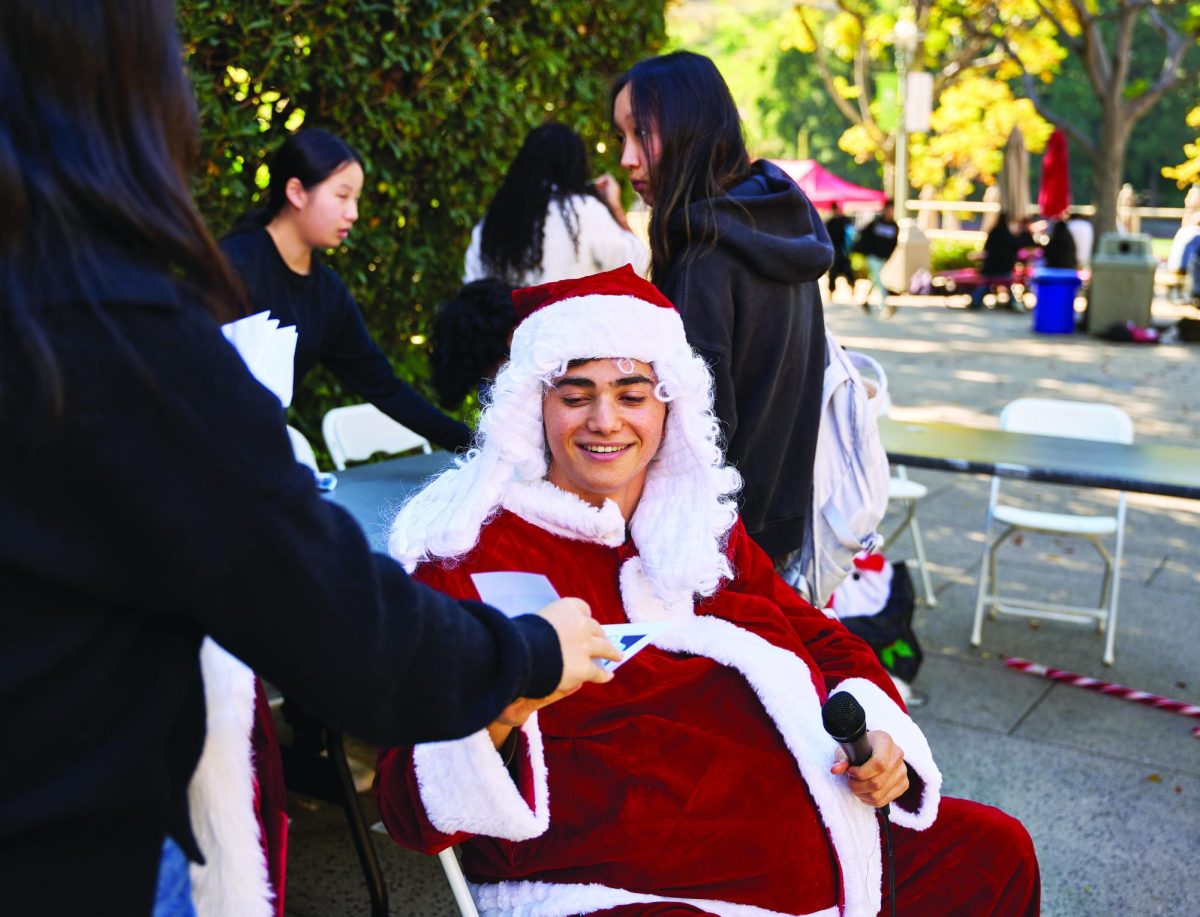 A Community Council member hands a completed Winter-Gram to Rael Kreiz ’26 dressed up as Santa Claus.