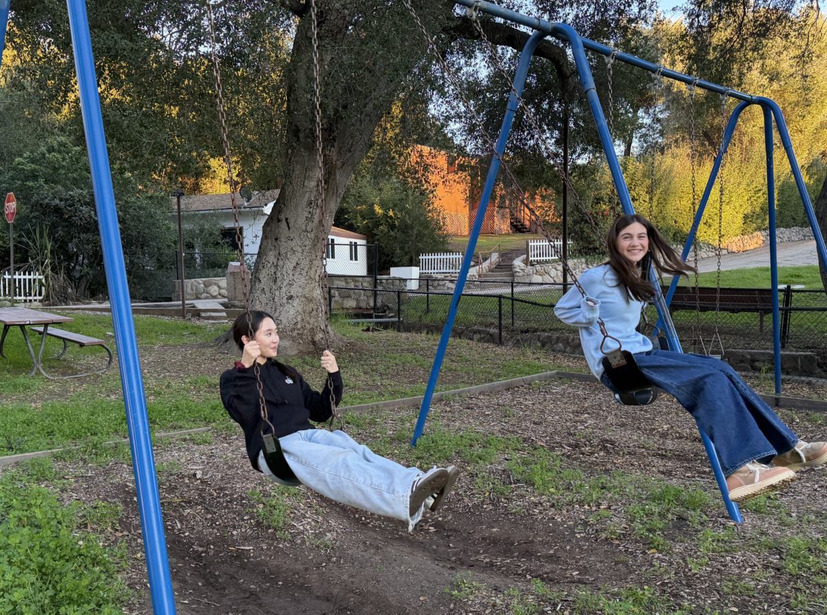 Chamber Singer Miley Lee '28 (left) and Bel Canto singer Grace Eisner '28 (right) relax on the swings during their free time at Camp Ramah Retreat Center in Ojai. 