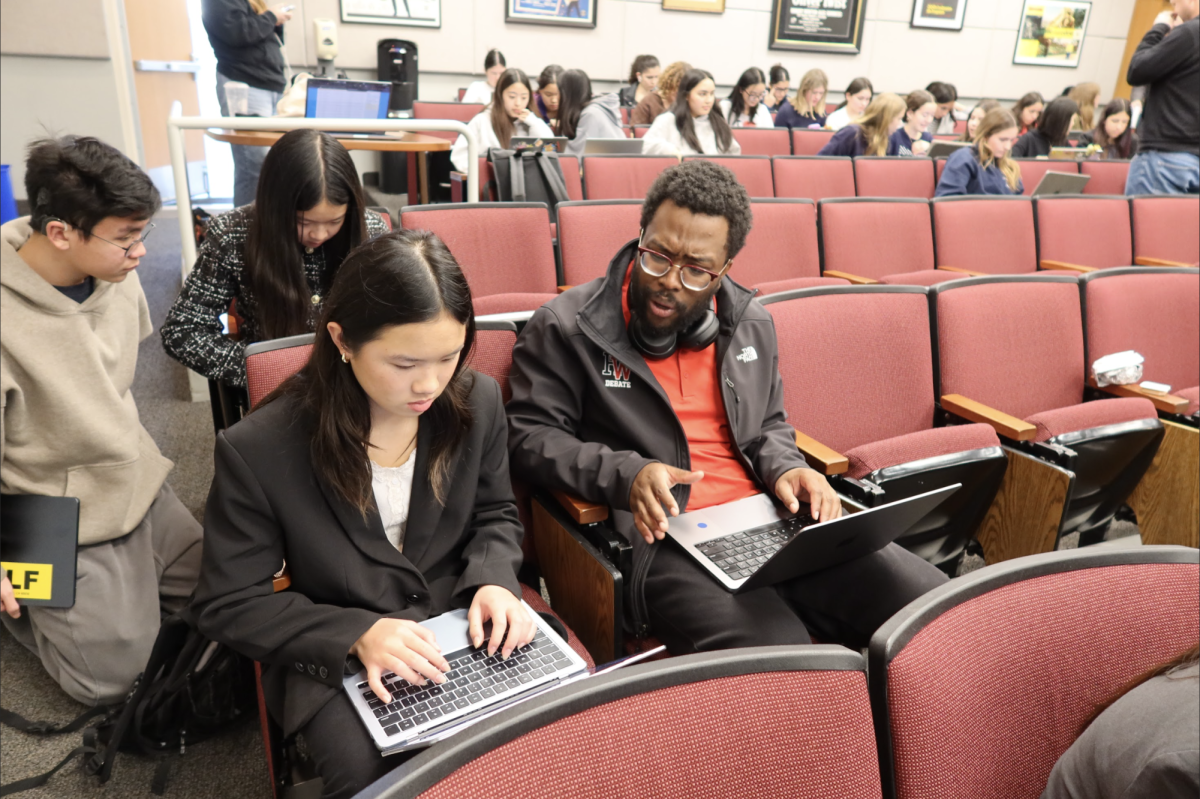 PREPPING THE ARGUMENTS: Upper School Debate Coach Khamani Griffin helps a school debater prepare prior to a round in Ahmanson Hall at the 12th annual Harvard-Westlake debate tournament.