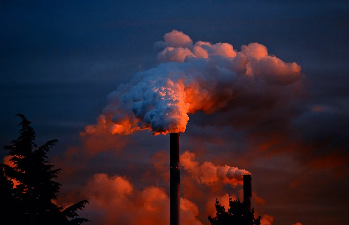 A textile factory sends a a plume of smoke snaking through the air. 
