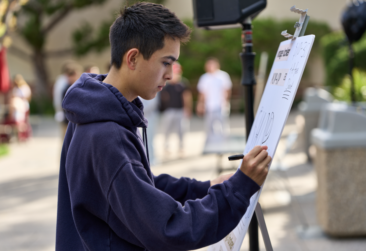 Beckham Williams '28 writes the prices on poster board as the pop-up store opens. 